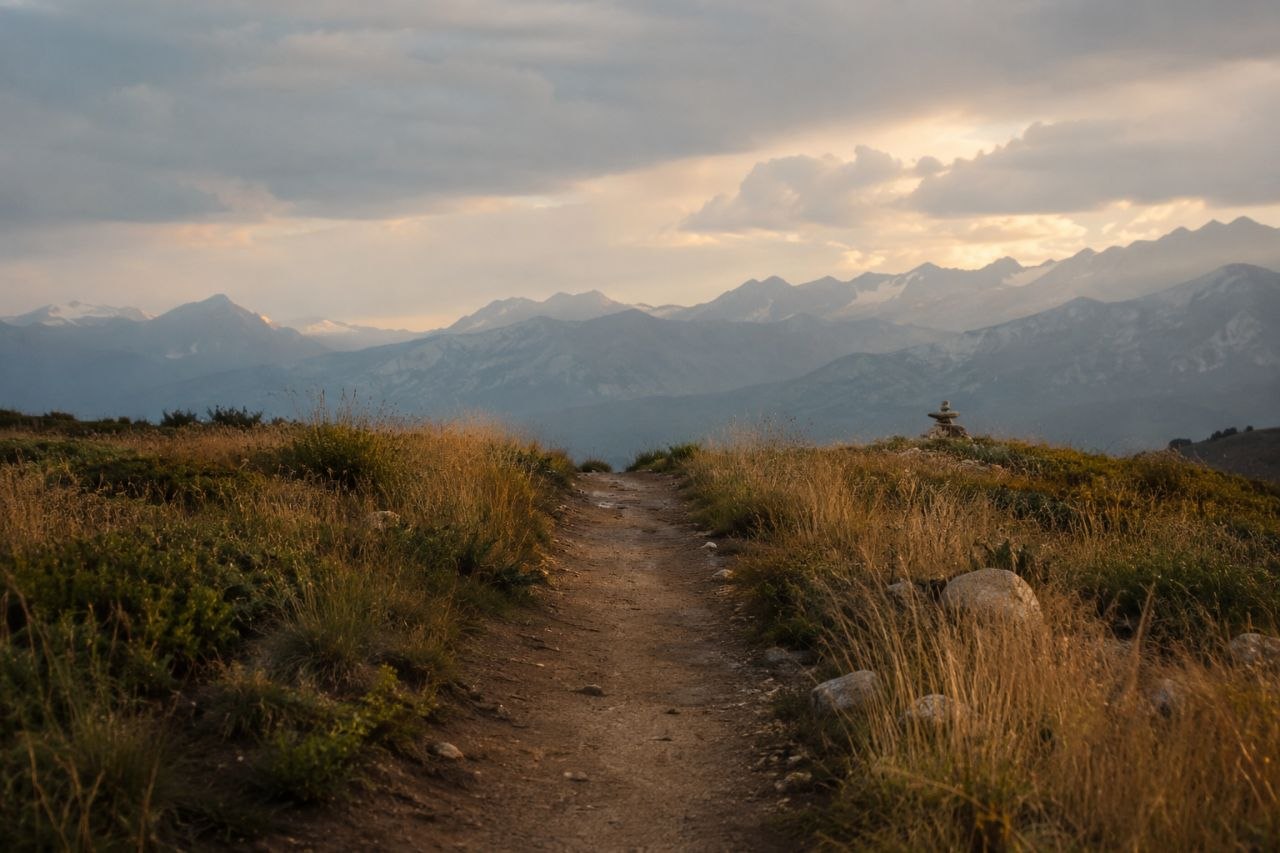 A mountain path under shifting weather, opening toward distant peaks